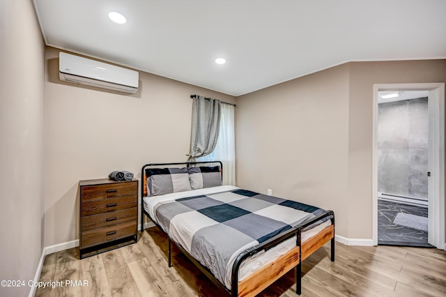 bedroom with baseboards, a wall unit AC, and light wood finished floors