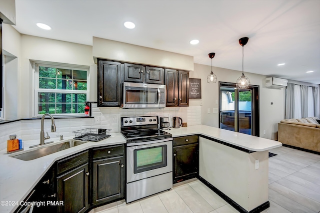 kitchen with appliances with stainless steel finishes, light countertops, a wall mounted air conditioner, and a sink