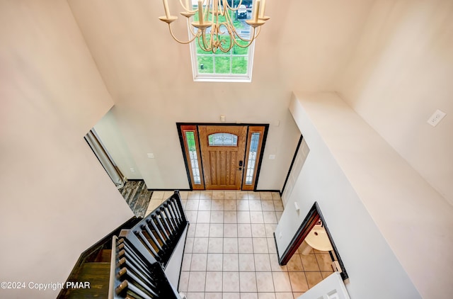 foyer entrance featuring light tile patterned flooring, a towering ceiling, and a notable chandelier