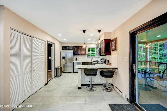 kitchen featuring stainless steel appliances, light countertops, backsplash, baseboard heating, and a peninsula