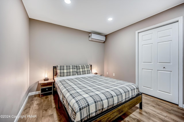 bedroom with recessed lighting, baseboards, wood finished floors, and a wall mounted air conditioner