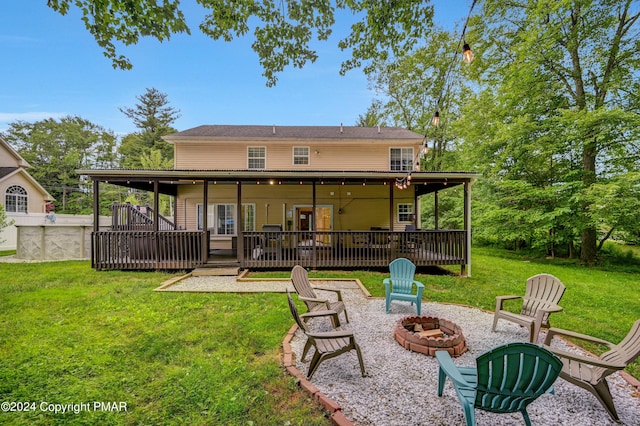 back of house with a deck, a patio area, a lawn, and a fire pit