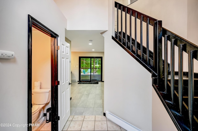 stairs featuring a baseboard heating unit, a baseboard radiator, baseboards, and tile patterned floors