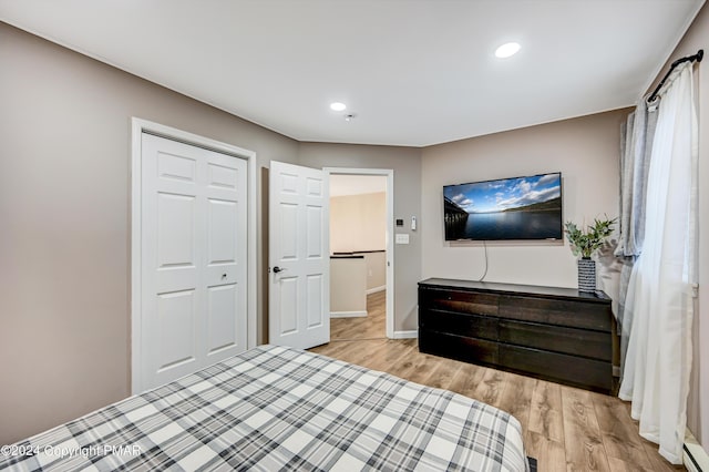 bedroom with baseboards, light wood-style flooring, baseboard heating, a closet, and recessed lighting