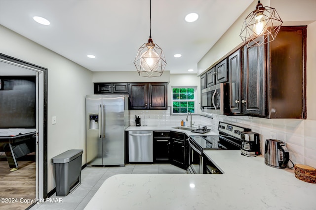 kitchen with tasteful backsplash, stainless steel appliances, light countertops, and decorative light fixtures