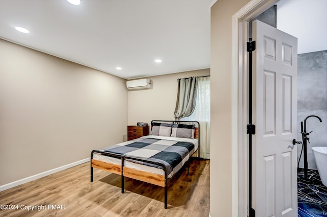 bedroom featuring recessed lighting, a wall unit AC, baseboards, and wood finished floors