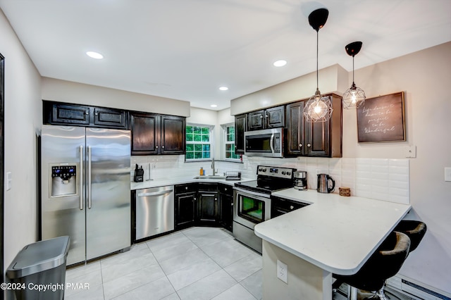 kitchen with light countertops, decorative backsplash, appliances with stainless steel finishes, a baseboard heating unit, and a sink