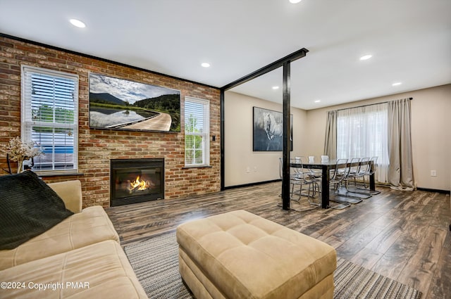 living area featuring a brick fireplace, plenty of natural light, brick wall, and wood finished floors