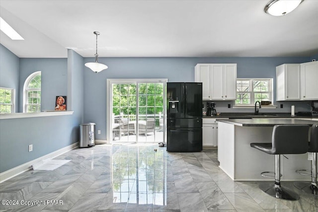 kitchen with baseboards, a sink, white cabinets, dark countertops, and black refrigerator with ice dispenser