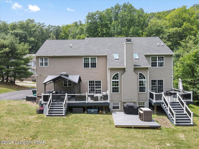 rear view of property featuring stairway, roof with shingles, a lawn, a chimney, and a deck