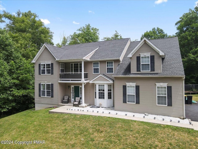 view of front of property featuring a patio area, a balcony, and a front yard