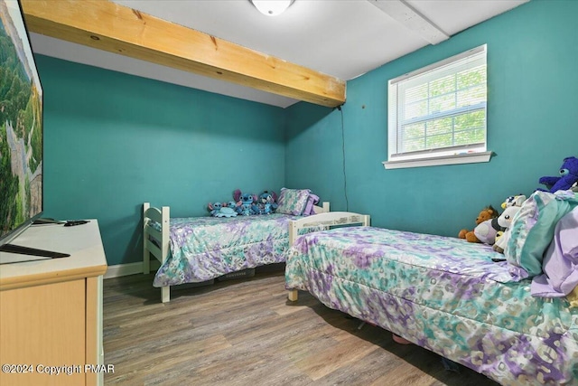 bedroom with beamed ceiling, baseboards, and wood finished floors