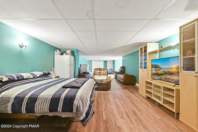 bedroom featuring wood finished floors, freestanding refrigerator, and a paneled ceiling