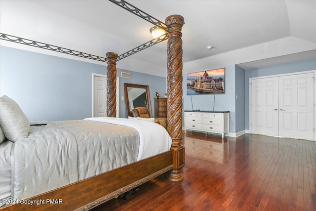 bedroom with visible vents, baseboards, lofted ceiling, hardwood / wood-style flooring, and a closet