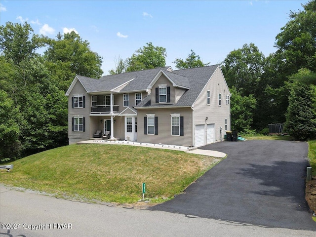 view of front of house featuring a front yard, a balcony, driveway, an attached garage, and a shingled roof