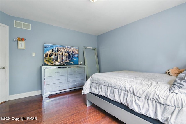 bedroom featuring visible vents, baseboards, and wood finished floors