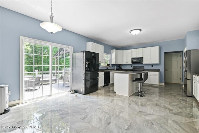 kitchen featuring marble finish floor, black appliances, a kitchen breakfast bar, dark countertops, and white cabinets