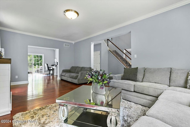 living room with visible vents, wood finished floors, crown molding, baseboards, and stairs