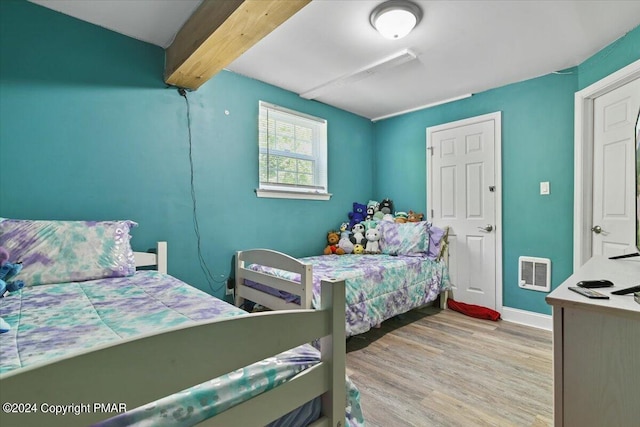 bedroom featuring visible vents, beam ceiling, baseboards, and wood finished floors