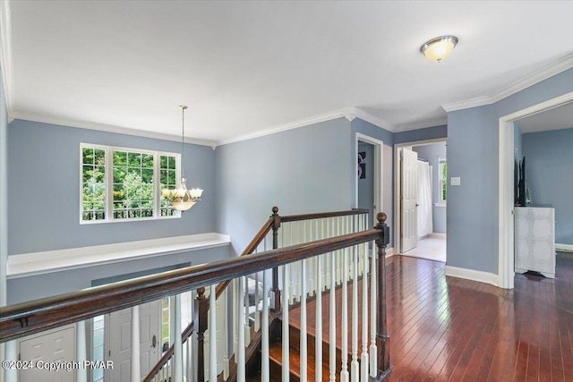 hallway featuring baseboards, an inviting chandelier, dark wood-type flooring, crown molding, and an upstairs landing