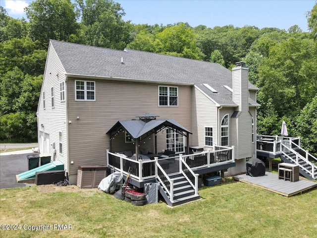 back of property with a deck, a yard, a chimney, and a shingled roof