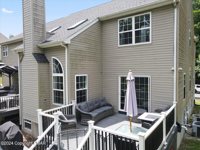 rear view of house with a chimney, roof with shingles, and outdoor lounge area