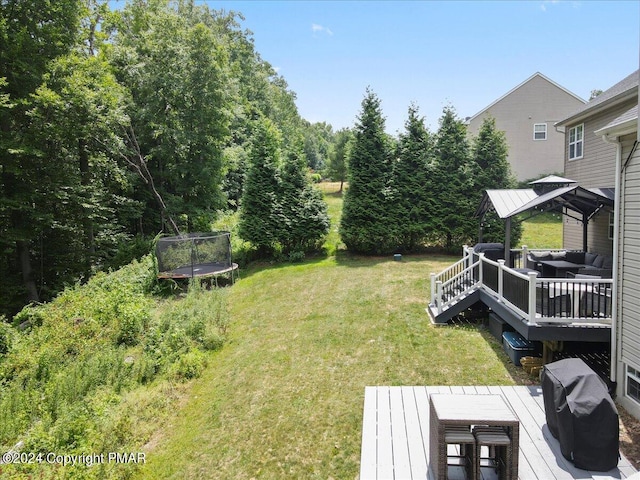 view of yard featuring a gazebo, a deck, an outdoor hangout area, and a trampoline