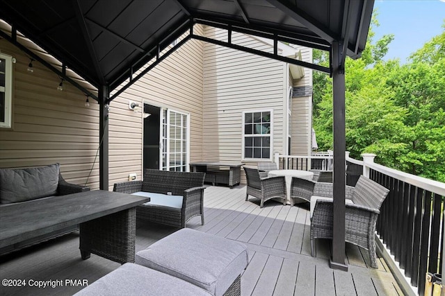 wooden terrace featuring a gazebo, an outdoor hangout area, and outdoor dining space