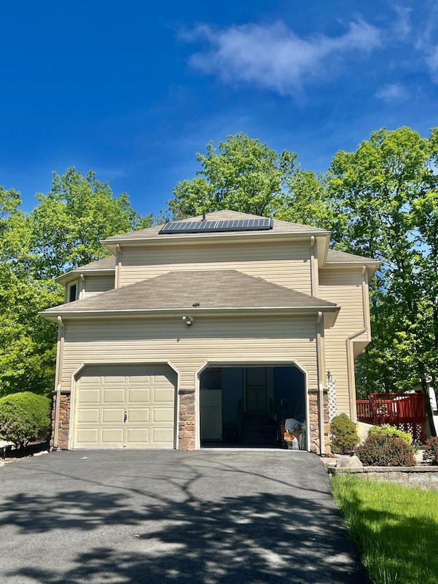 512 Bombur Ln, Tamiment, PA 18371 - view of front of house featuring solar panels, stone siding, driveway, and a garage