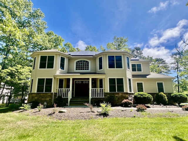 512 Bombur Ln, Tamiment, PA 18371 - view of front facade featuring covered porch, stone siding, solar panels, and a front lawn