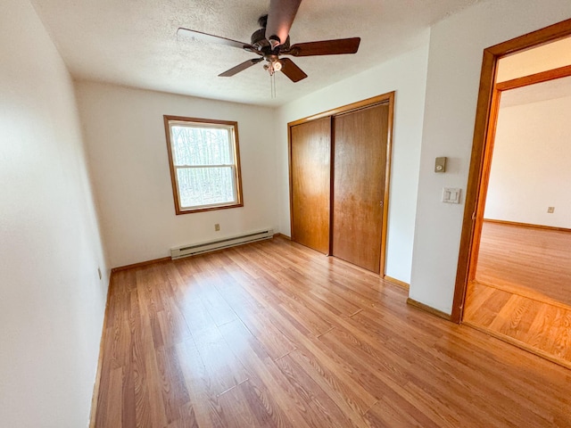 4751 Brentwood Dr, Tobyhanna, PA 18466 - unfurnished bedroom featuring a baseboard heating unit, light wood finished floors, a closet, a ceiling fan, and baseboards