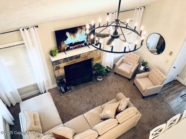 living area featuring a textured ceiling, a fireplace, baseboards, and a notable chandelier