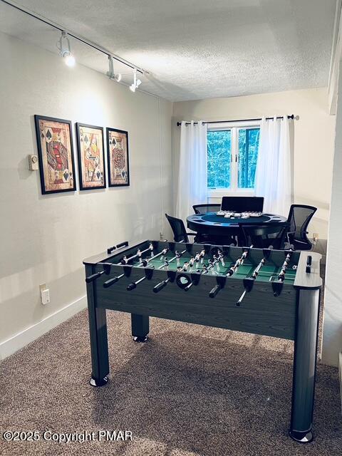 playroom featuring carpet, baseboards, and a textured ceiling