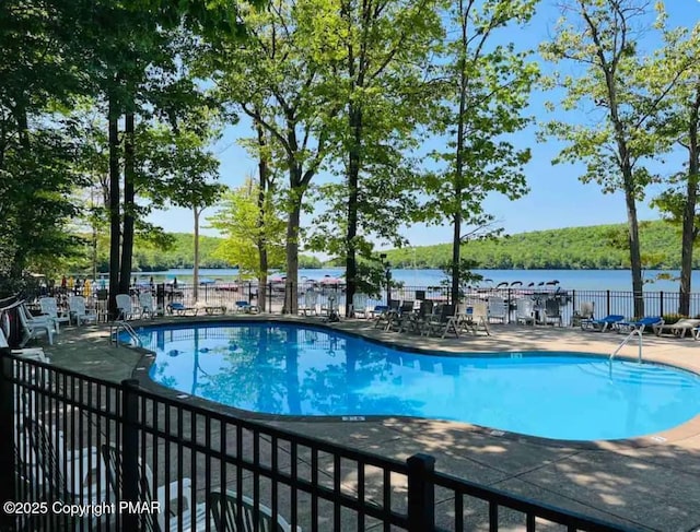 pool with a water view, fence, and a patio