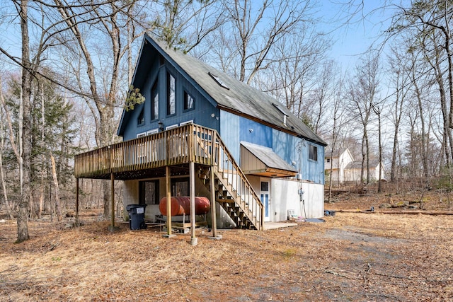 back of house with roof with shingles, a wooden deck, and stairs