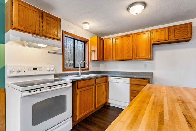 kitchen with white appliances, butcher block countertops, dark wood-type flooring, under cabinet range hood, and a sink