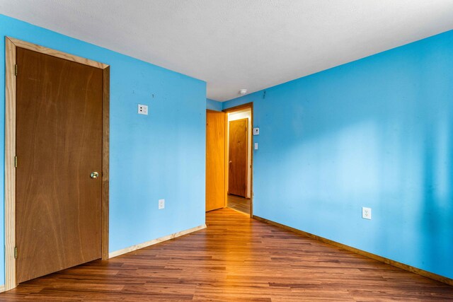 unfurnished room with baseboards and wood finished floors