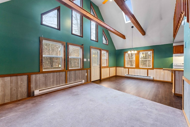 carpeted empty room featuring a baseboard heating unit, wainscoting, a chandelier, and beam ceiling