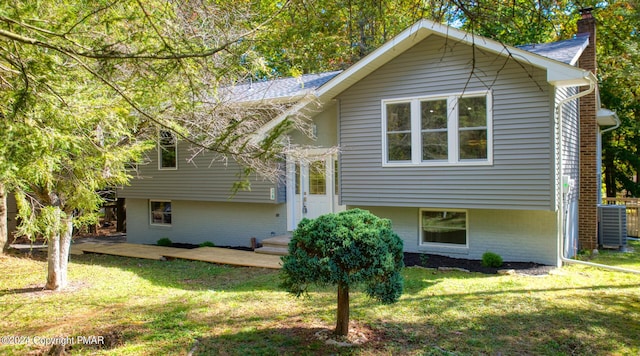 rear view of property featuring a yard, brick siding, cooling unit, and a chimney