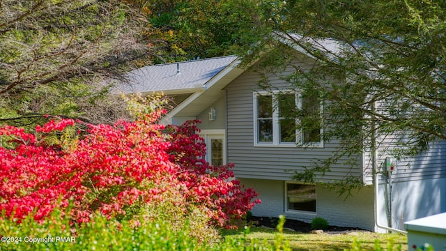 view of property exterior with brick siding and a shingled roof