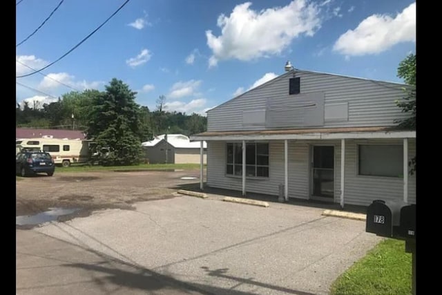 rear view of property featuring a porch and uncovered parking