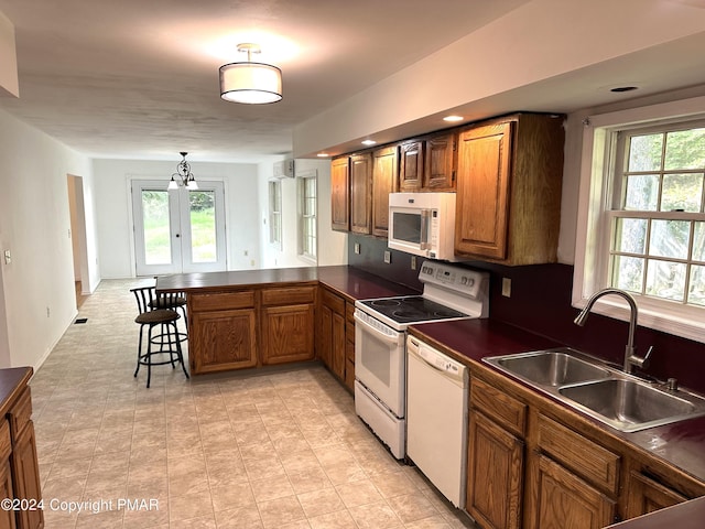 kitchen featuring dark countertops, white appliances, brown cabinets, and a peninsula