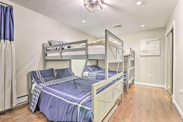 bedroom with recessed lighting, visible vents, a textured ceiling, wood finished floors, and baseboards