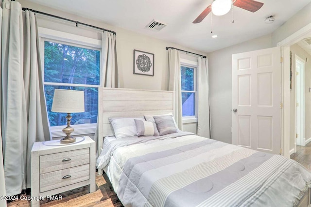 bedroom with wood finished floors, visible vents, and a ceiling fan