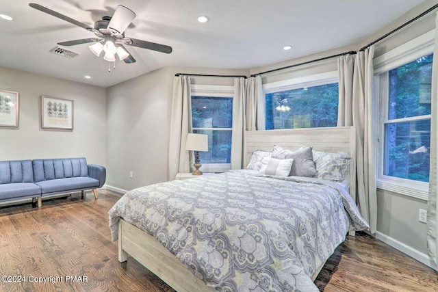 bedroom with wood finished floors, visible vents, and baseboards