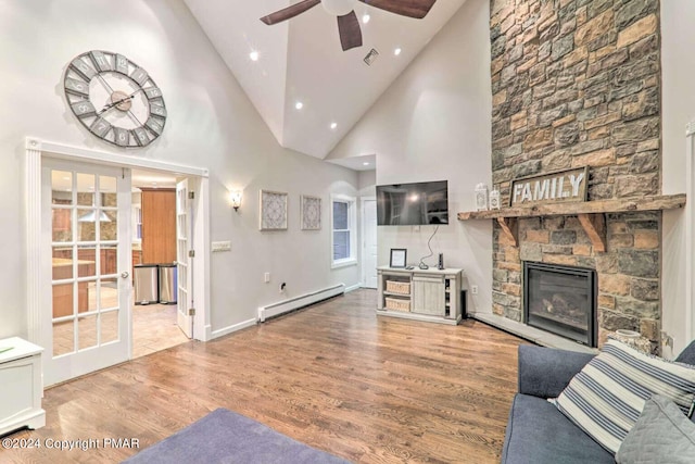 unfurnished living room featuring french doors, a baseboard radiator, visible vents, a stone fireplace, and wood finished floors