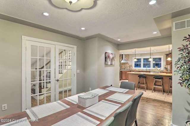 dining space with light wood-style floors, recessed lighting, visible vents, and a textured ceiling