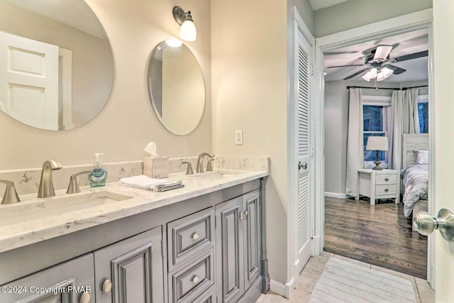 full bath featuring ceiling fan, double vanity, a sink, and baseboards