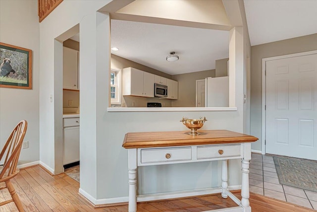 2181 Oak Hill Dr, Buck Hill Falls, PA 18323 - kitchen featuring white cabinets, baseboards, light countertops, freestanding refrigerator, and stainless steel microwave