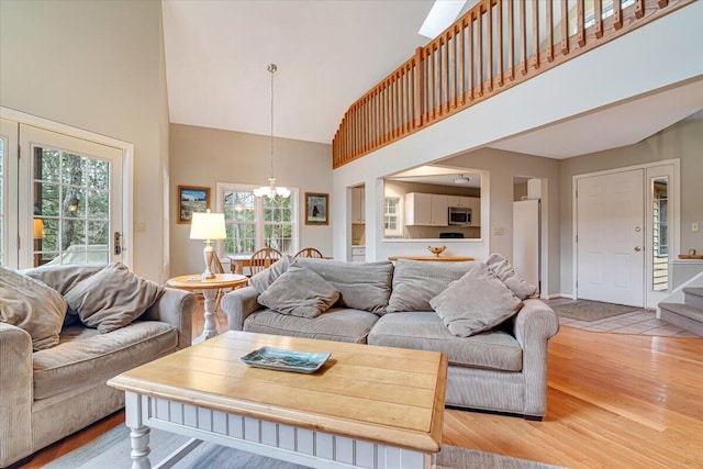 2181 Oak Hill Dr, Buck Hill Falls, PA 18323 - living area featuring a chandelier, light wood-style floors, high vaulted ceiling, and stairs